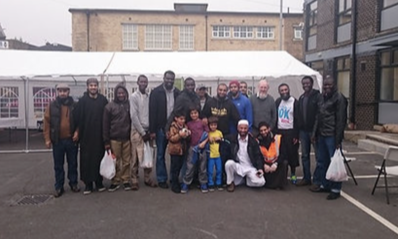 A group of adults and three children posing lined up in front of a gazebo.